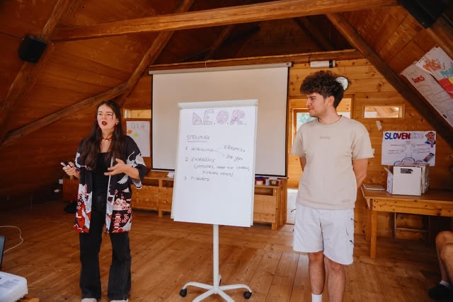 Doi participanți Job Jam prezentând lângă un flipchart, într-o mansardă de lemn