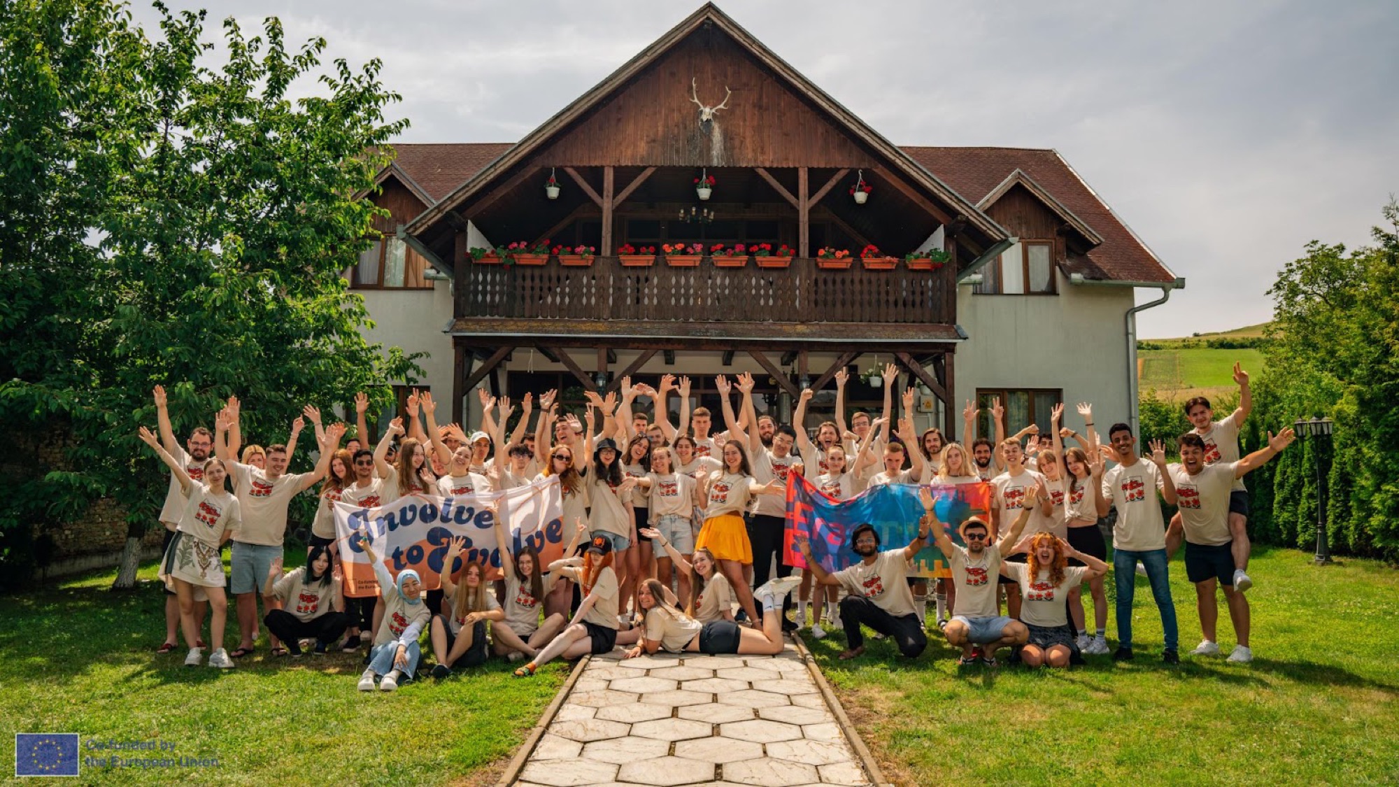 Participants of an Elemdiar youth exchange cheering in front of the guesthouse in Băgaciu
