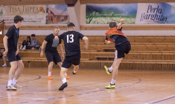 Un jucător în negru șutează în timpul unui meci în sala de sport